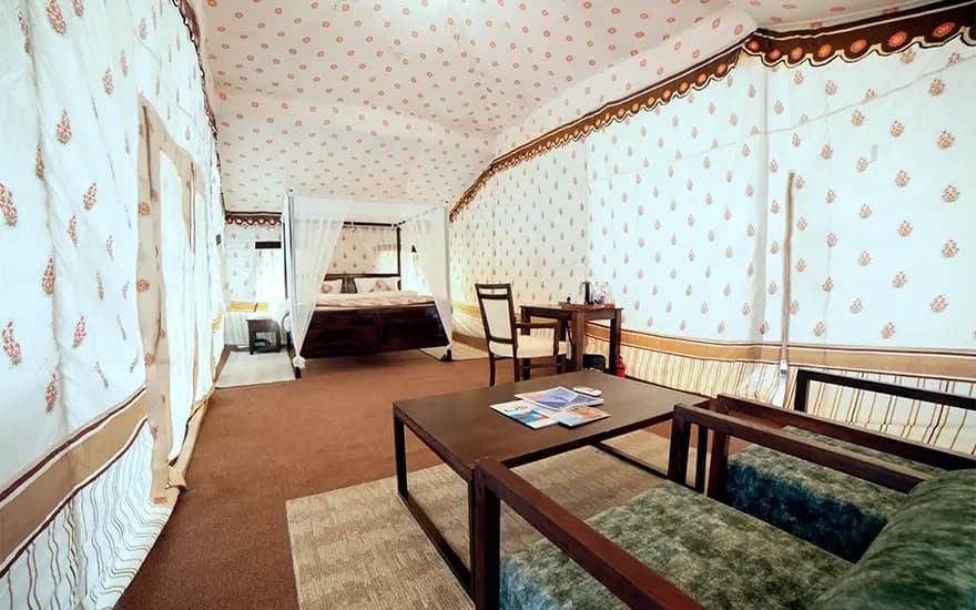 Bedroom beyond sitting area with two chairs and table at Rann Utsav — reference