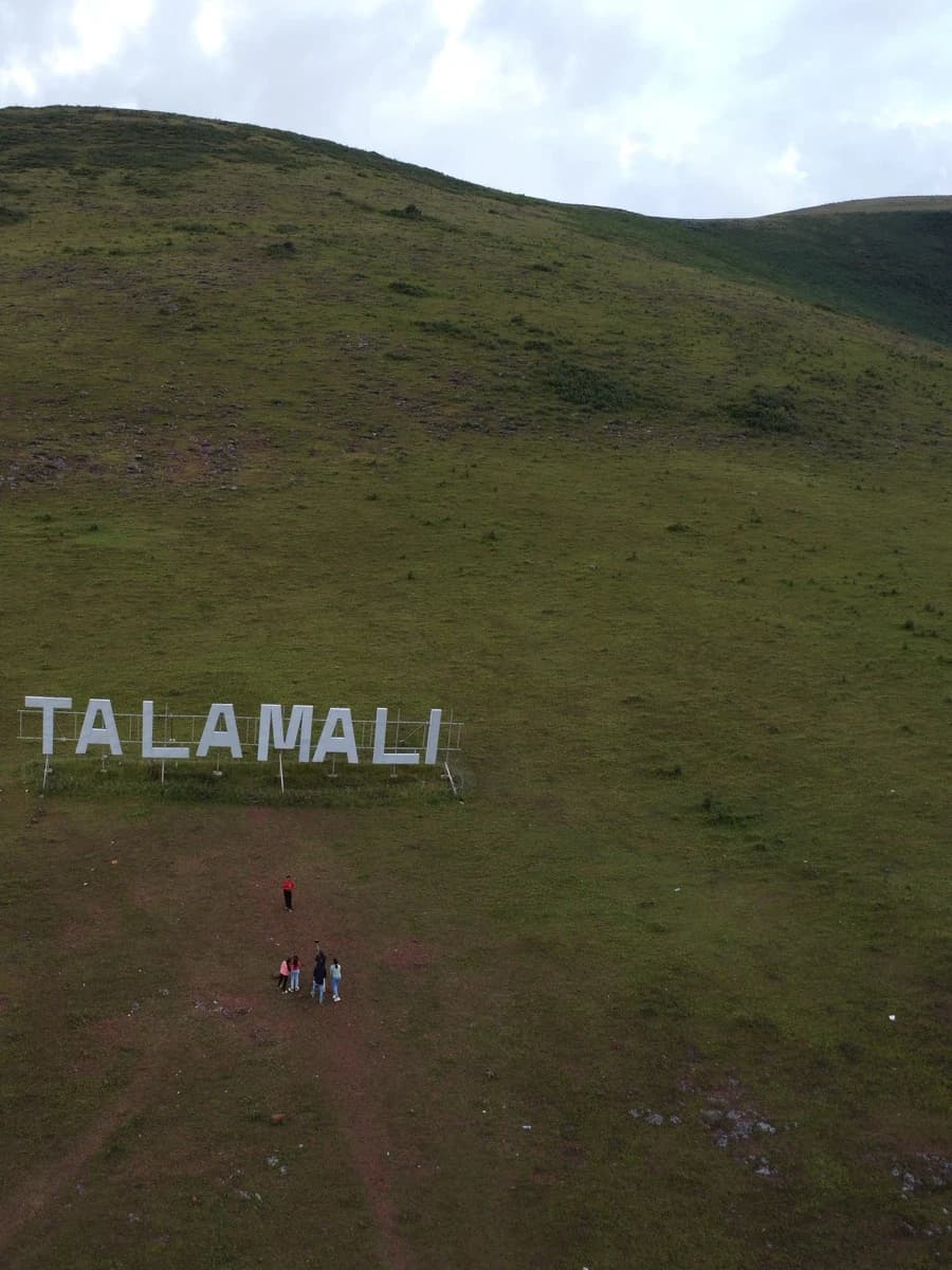 Visitors below the physical Talamali hilltop sign in Koraput